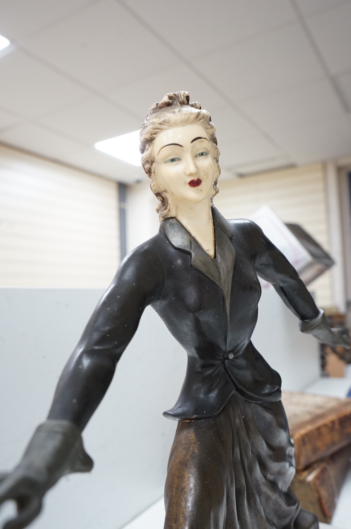 An Art Deco French spelter and ivorine model ‘Walkies Lady and Dog’, on a black marble and cream onyx base, 75cm long